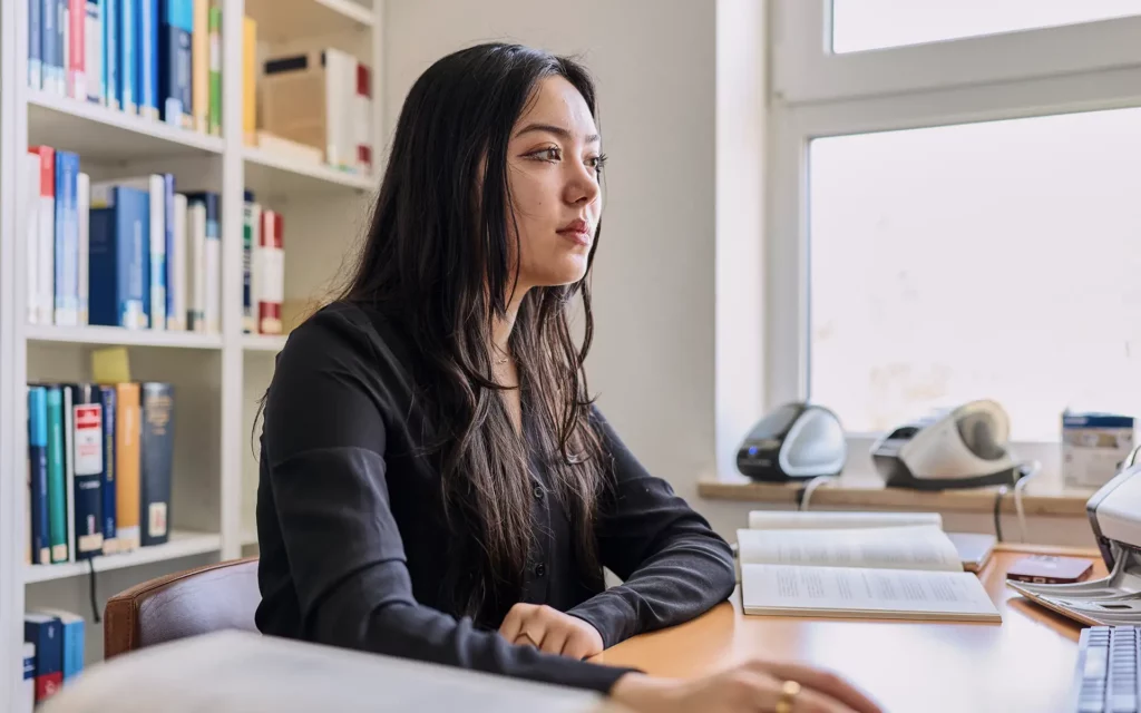 Jura-Studentin am Schreitisch sitzend und am arbeiten am Computer